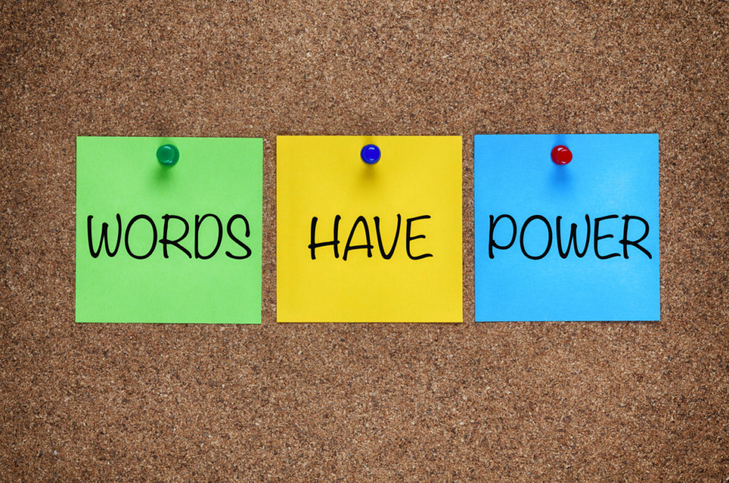 Three blanks post-it notes with phrase Words Have Power on corkboard.
