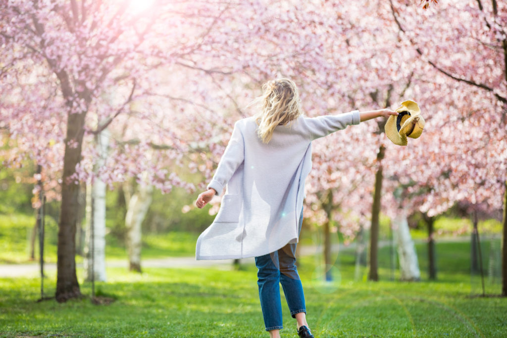 Happen woman walking into blooming cherry trees