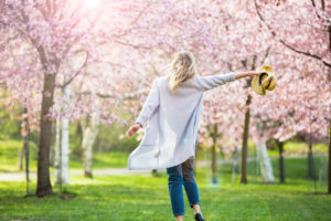 Happen woman walking into blooming cherry trees