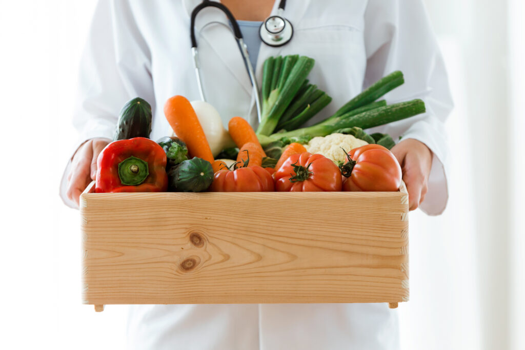 Nutritionist holding wooden box with fresh vegetables