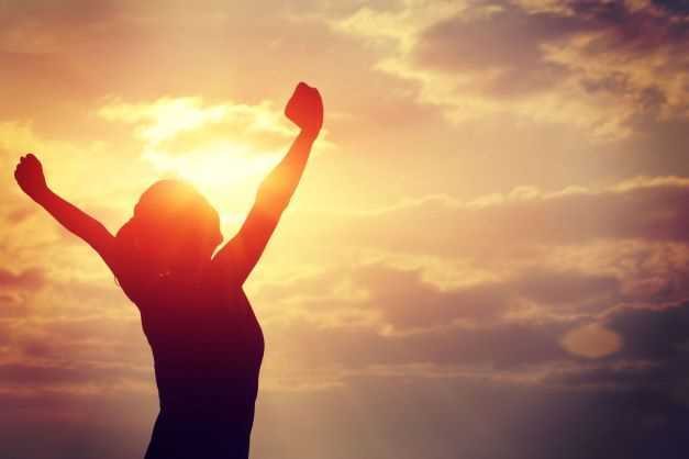 Happy Person raising arms to a morning sun